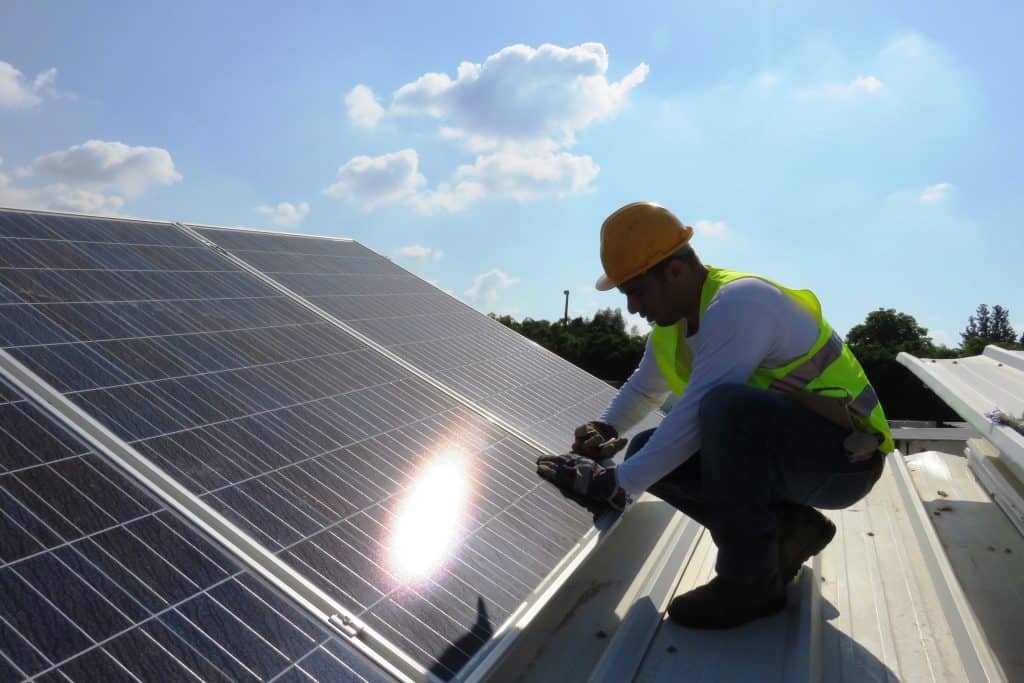 Man installing alternative energy photovoltaic solar panels on roof