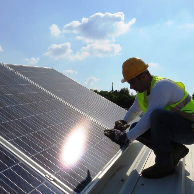 Man installing alternative energy photovoltaic solar panels on roof